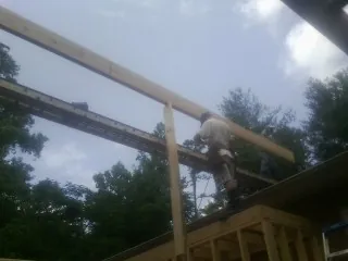 Carpenter setting a ridge beam over a new addition frame — Ice Dam Removal by Roofing Brothers in Sabina