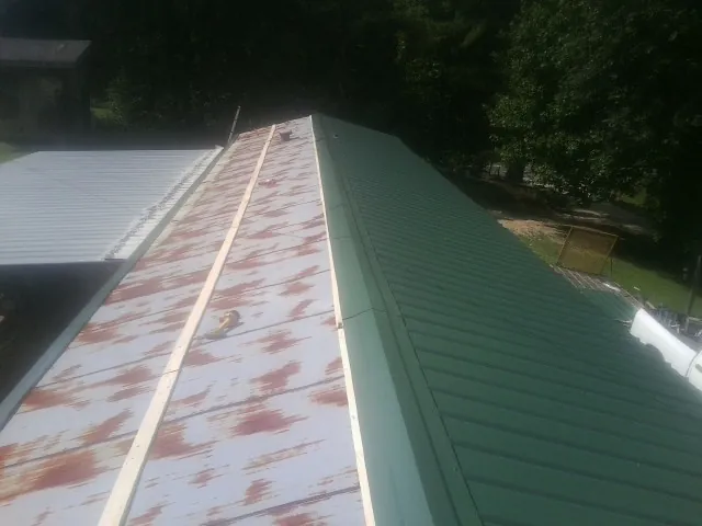 Old rusted panels beside newly installed green metal roofing — Wind Damage Roof Repair by Roofing Brothers in Sabina