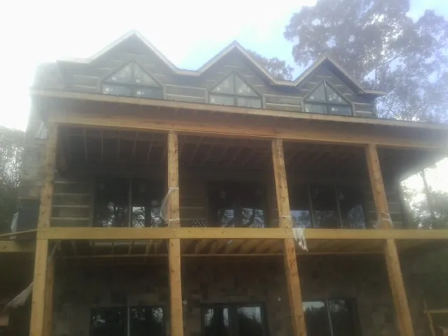 Dormers and porch framing on a large log home under construction — Roof Coating work by our crew in Sabina