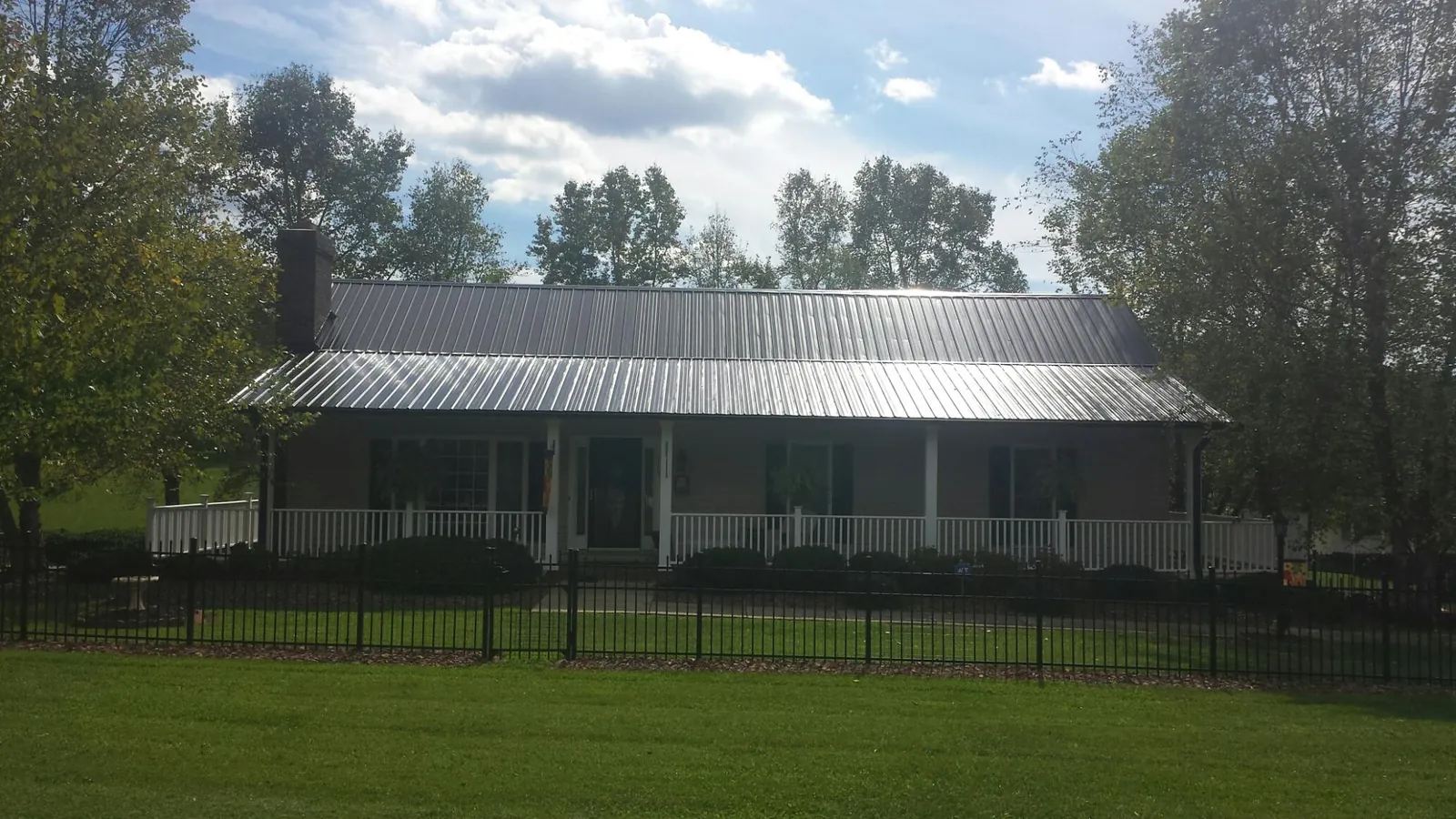 Gray metal roof on a brick ranch with a full width front porch — Gutter Guard Installation work by our crew in Sabina