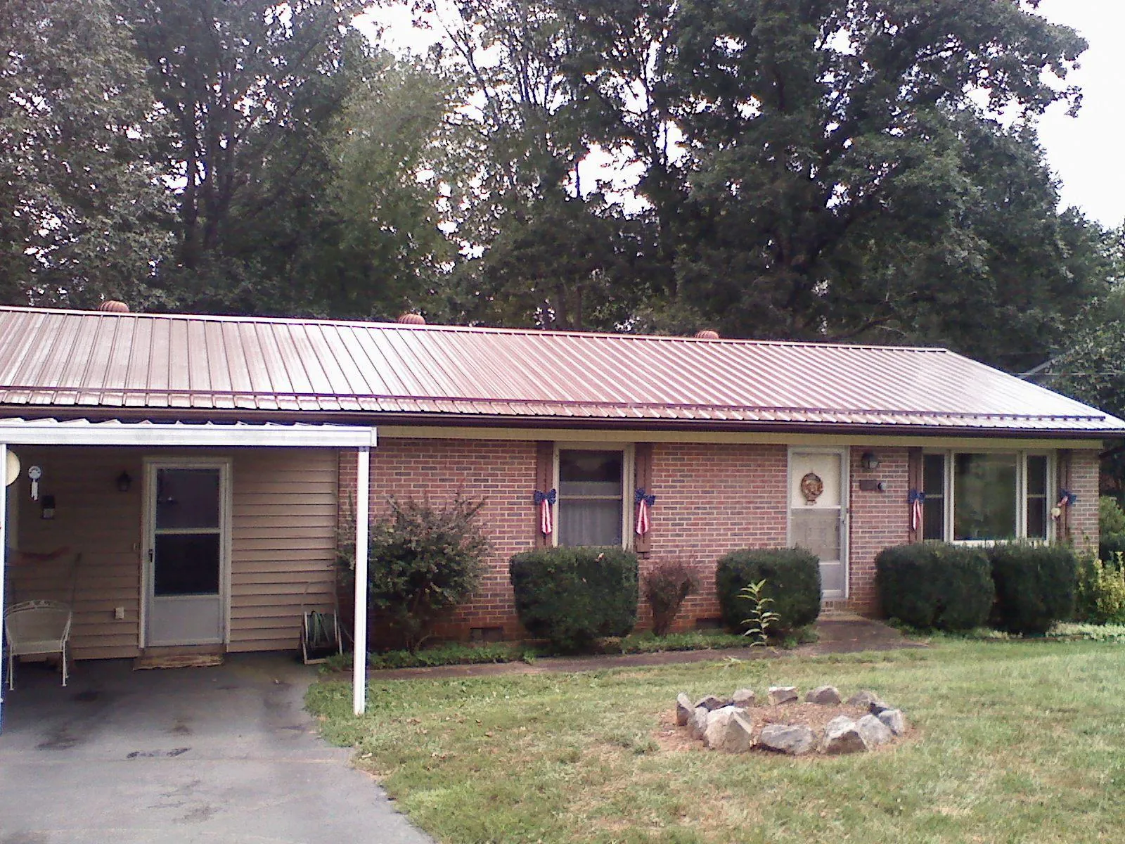 Bronze metal roof and carport on a brick ranch home — Roof Repair work by our crew in Sabina