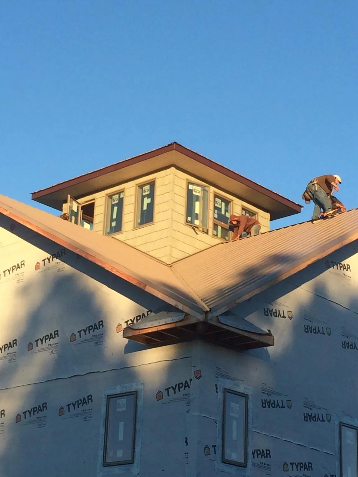 Roofers working around a rooftop cupola on a new metal roof at sunset — Roof Waterproofing in Sabina by Roofing Brothers